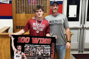  student holding winning banner that says "100 wins"